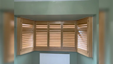 Light wood bay window shutter in Sheffield with sage green walls