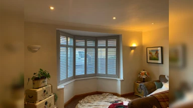 Grey window shutters fitted in a bay window