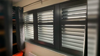 Full height window shutter with a black frame a nd white slats