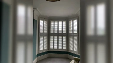 Slate blue walls with tier on tier window shutters in a bay window