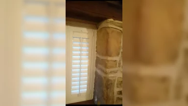 White window shutter fitted into an even stone wall window opening