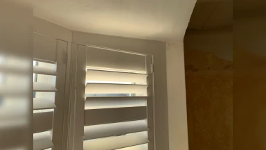 Neatly fitted white window shutters fitted into an out of square window opening