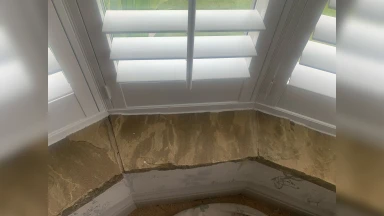Bay window shutters fitted into an even stone window surround