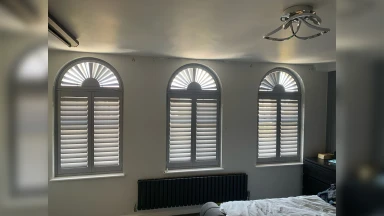 Three identical arch shaped bedroom window shutters
