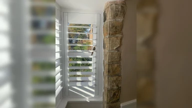 Looking through window shutter that is well fitted against an even stone wall