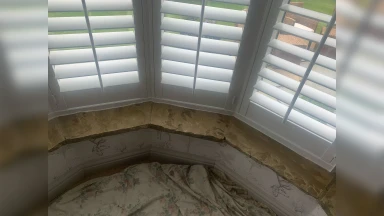 Bay window shutters fitted into an even stone window surround