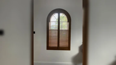 Dark wooden arch shaped window shutter