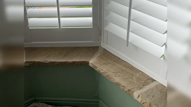 Close up show of bay window shutters fitted into an even stone window sill